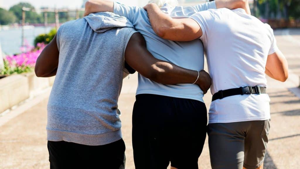 A group of three men walking arm in arm outdoors.
