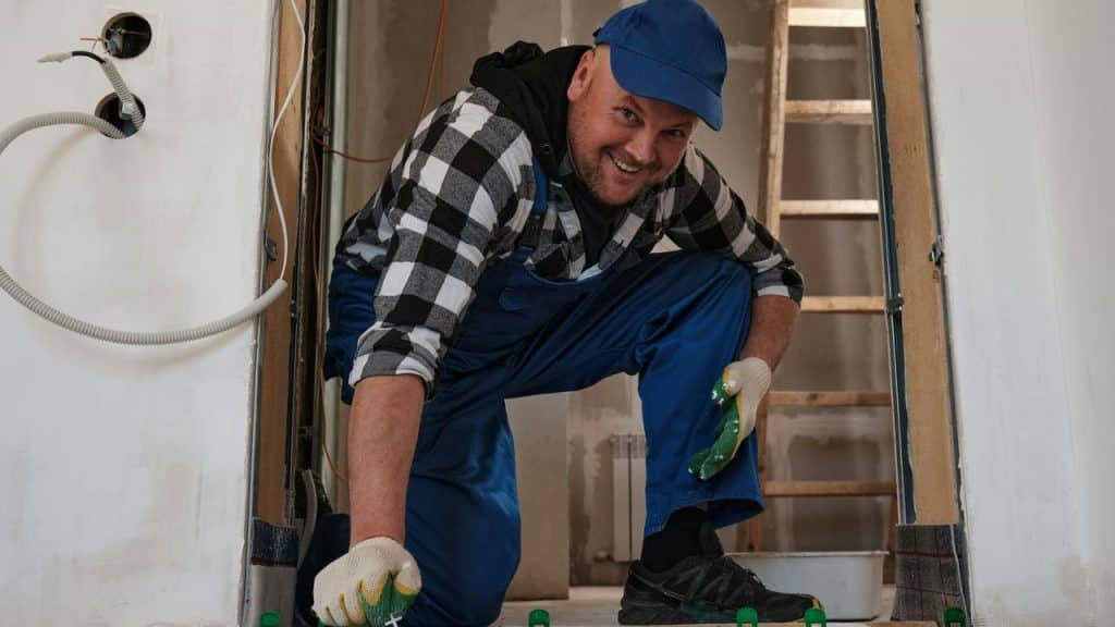 A worker installing floor tiles.