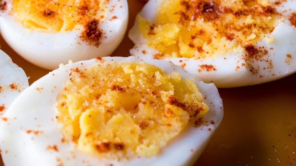 A close-up of halved hard‑boiled eggs dusted with paprika.