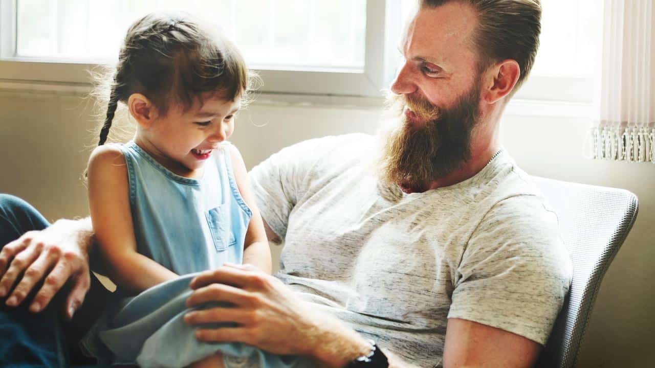 A bearded man smiling at a laughing child.