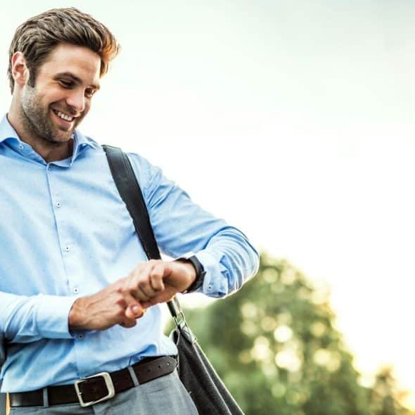 A smiling businessman checking his watch.
