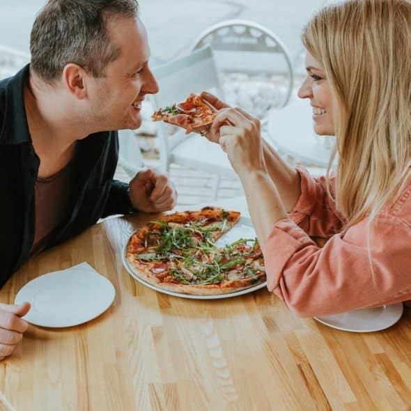 A couple sharing a pizza at a table.
