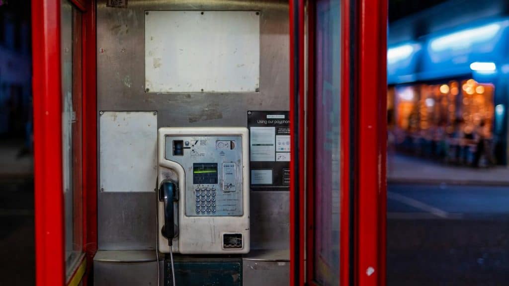 A payphone inside a red booth.