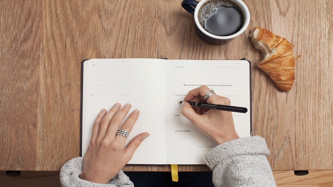 A person journaling with breakfast.