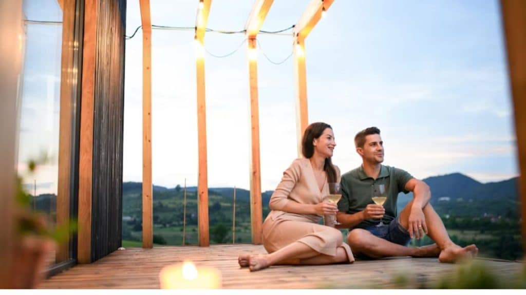 Couple with wine are  enjoying the peaceful view outside of their home