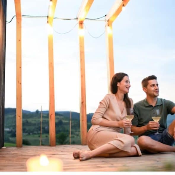 Couple with wine are enjoying the peaceful view outside of their home