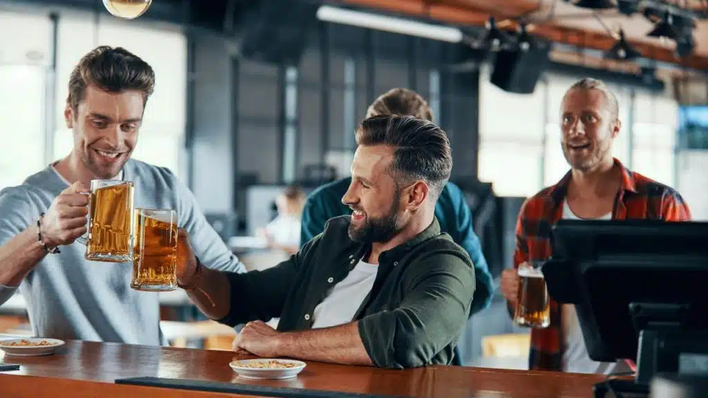 A group of men toasting with beers at a bar.