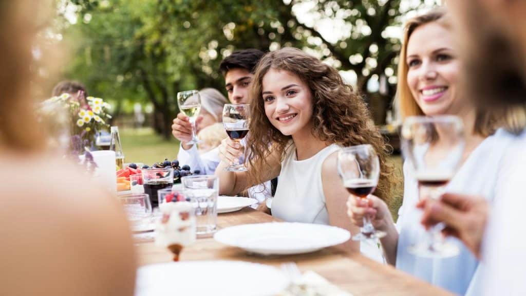 A group of friends toasting with wine at an outdoor table.