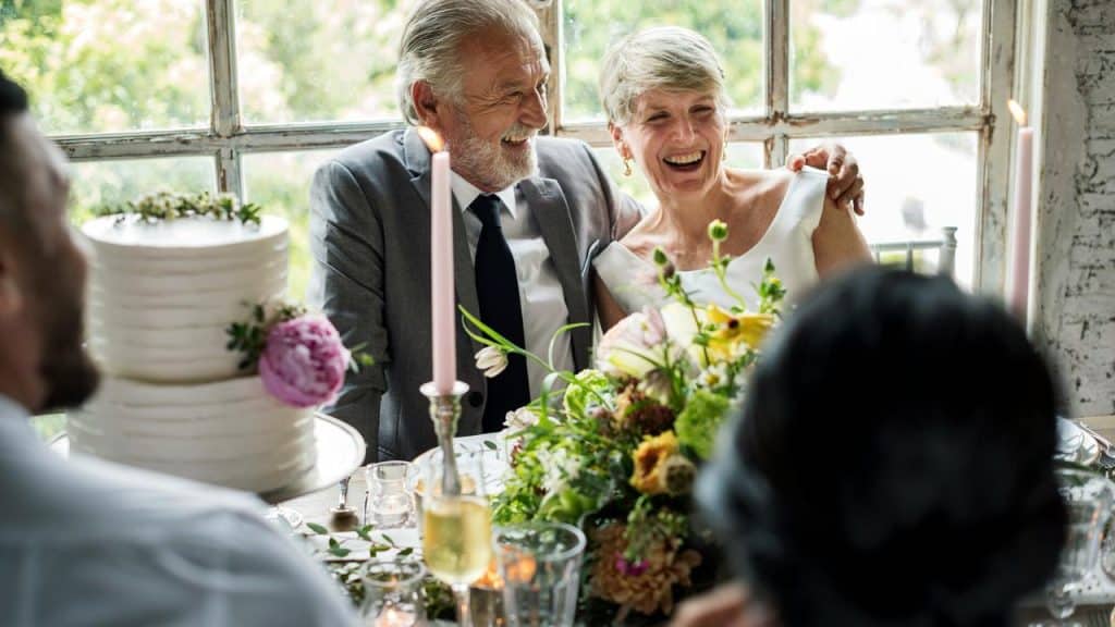 An older couple laughing at their wedding reception.