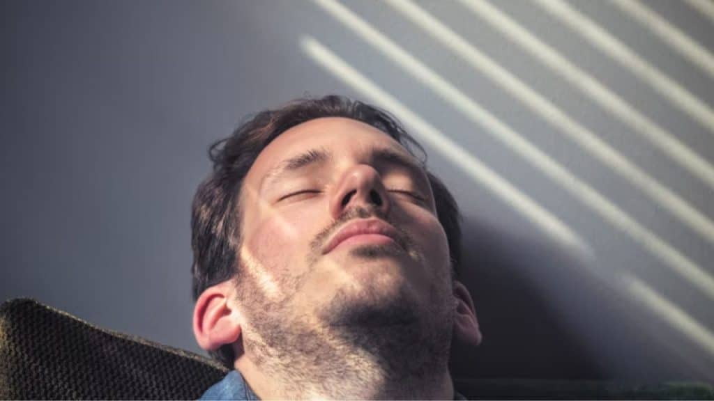 Man leaning back in his chair with eyes closed and deep breathing.