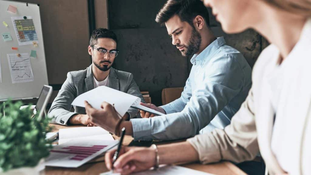 A group of professionals reviewing documents and charts around a table.