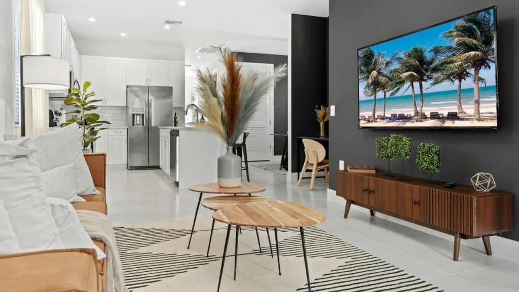 A wide shot of a modern living room with a large TV mounted on a dark wall.