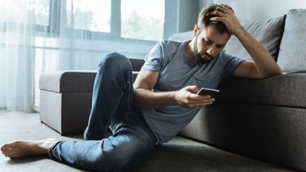 A man looking conflicted while typing a vague social post