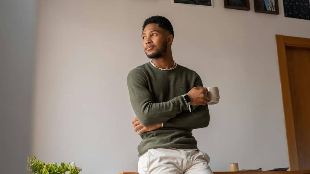 A man holding a mug, gazing thoughtfully.