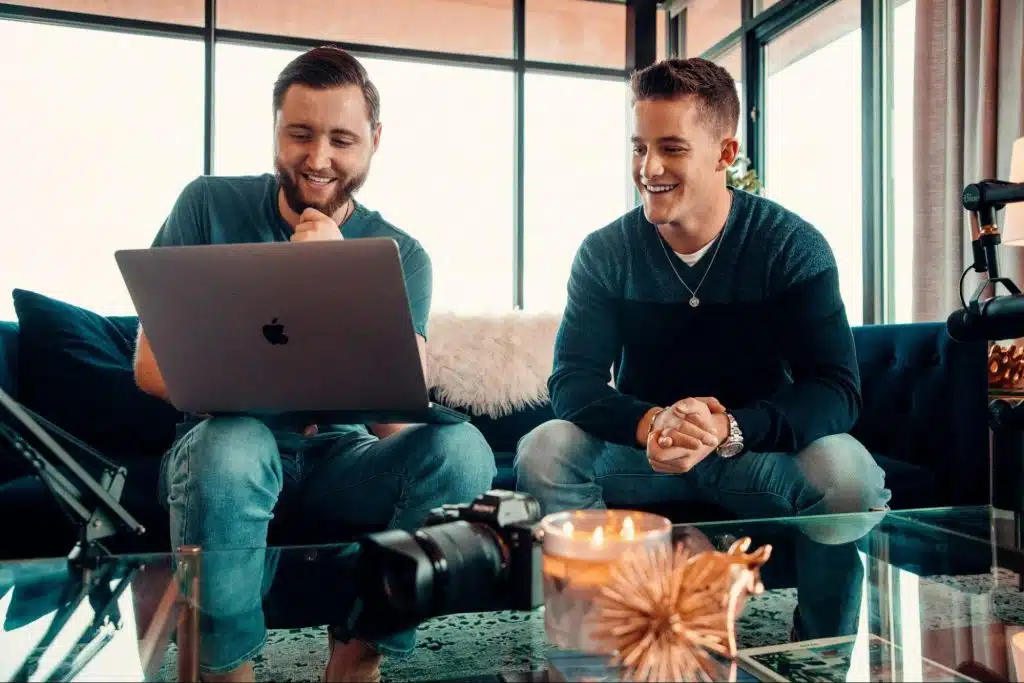 Two men sitting at the couch using a laptop.