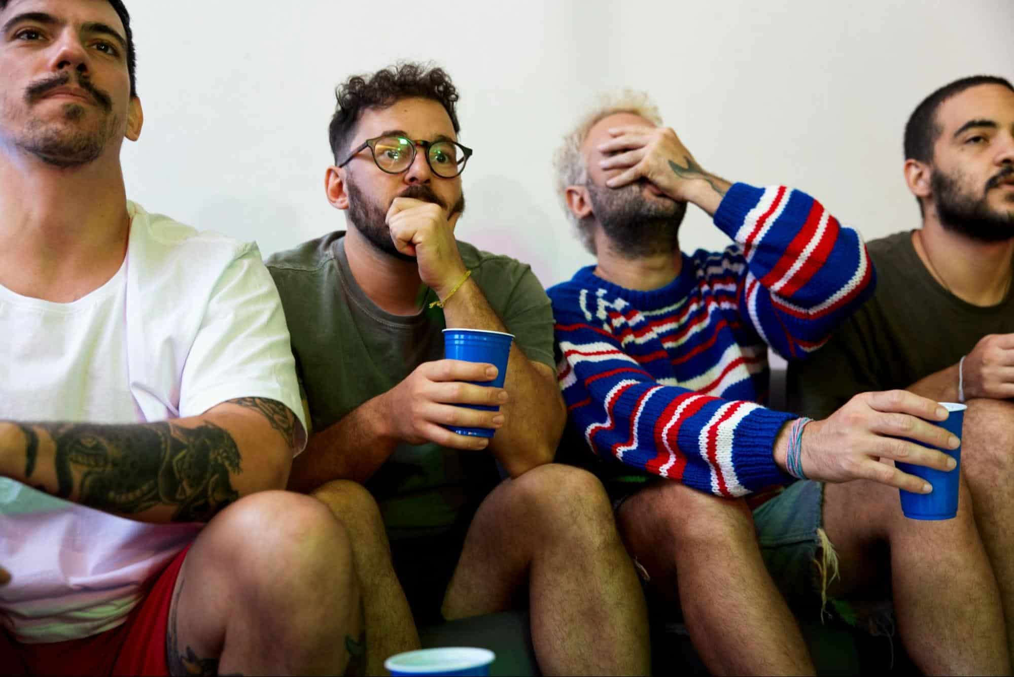 Men watching a movie and having a reaction.