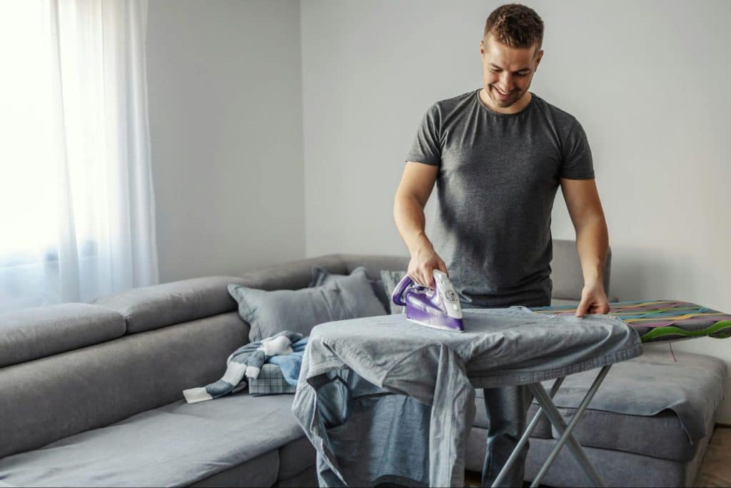 A man ironing his clothes.