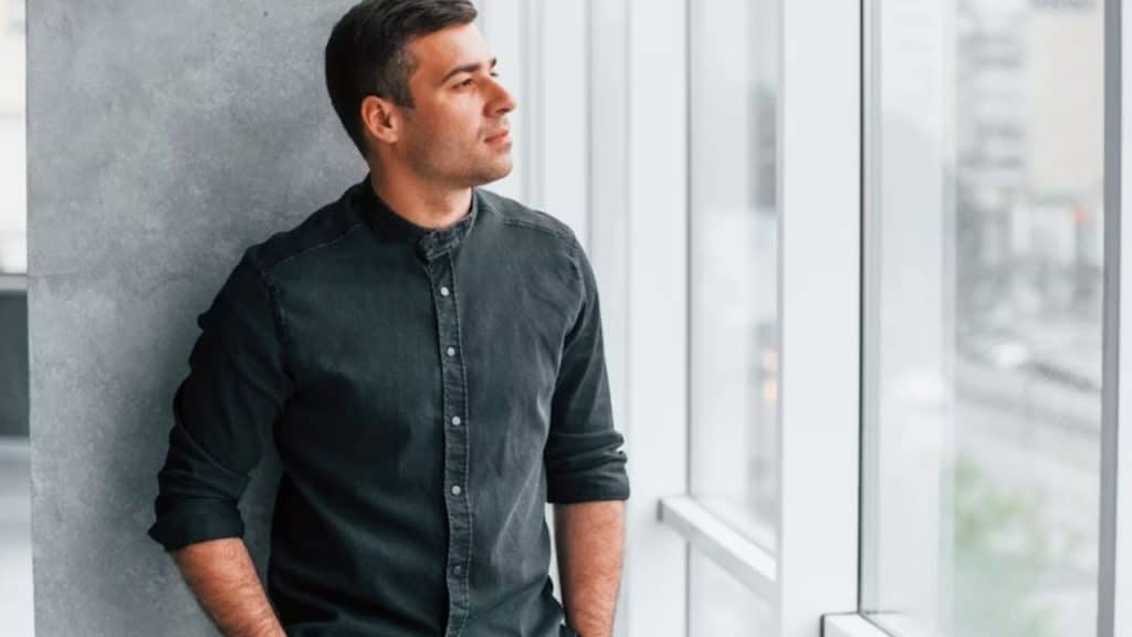 Man standing near the window reflecting while in a relationship