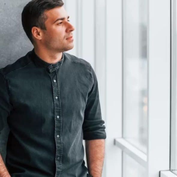 Man standing near the window reflecting while in a relationship