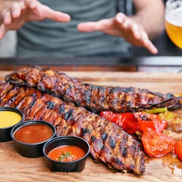A tray filled with barbecue meat and beer in a restaurant.