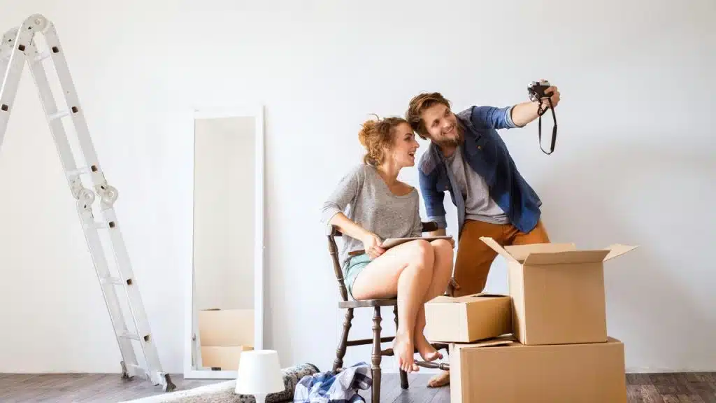 A couple unpacking boxes and taking a selfie.