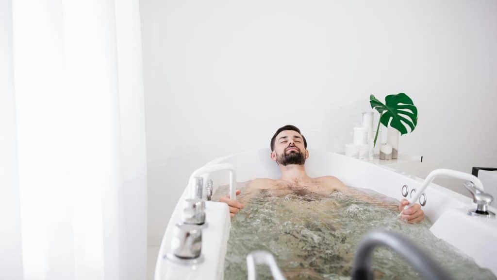 A man reclining in a bubbling bathtub.