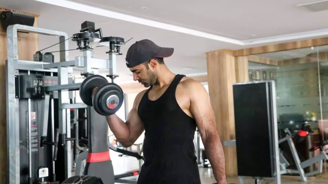 A man lifting weights with focused expression in a clean gym.