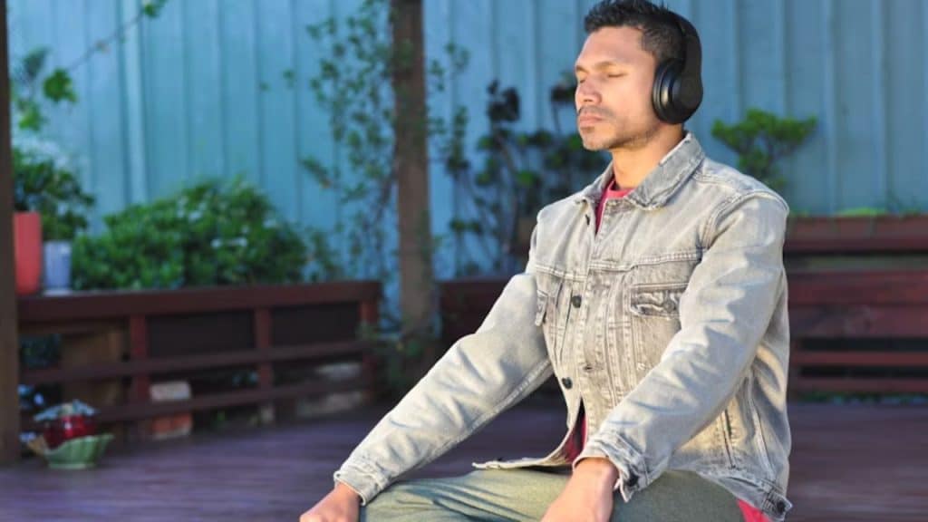 Man sitting alone outdoors, eyes closed, practicing mindfulness.