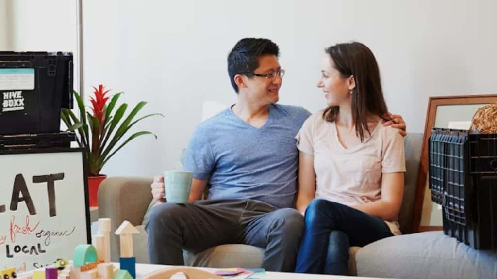 Couple sitting on a couch talking and making eye contact.