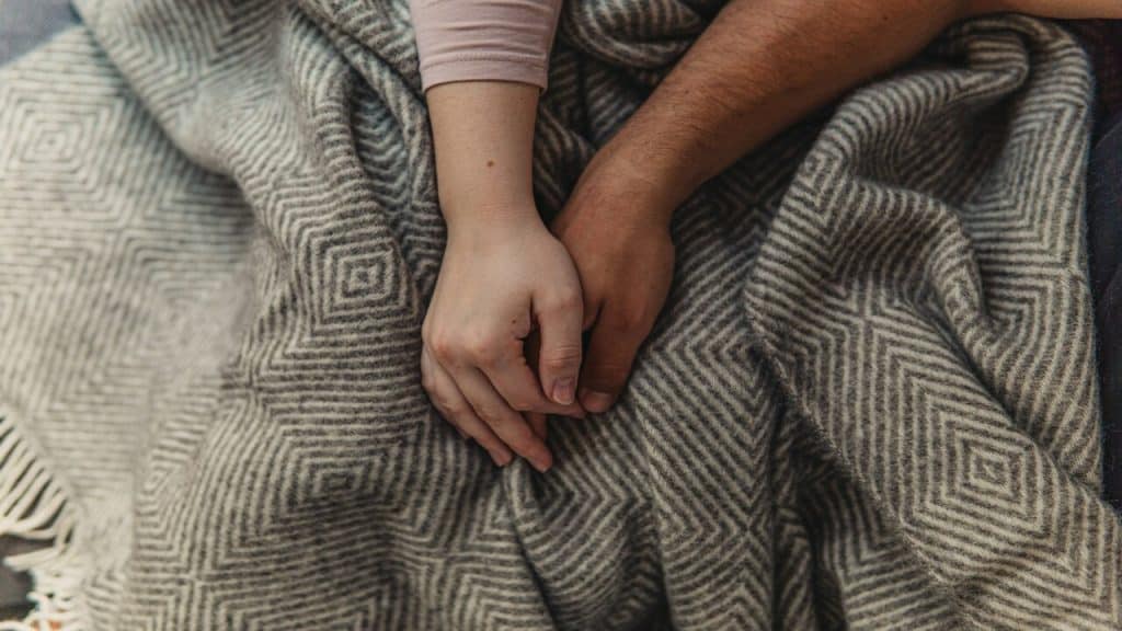 A couple holding hands in bed
