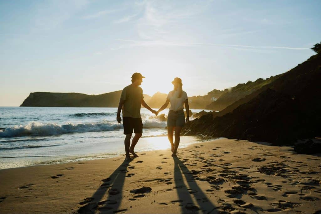 A couple holding hands while walking at the beach