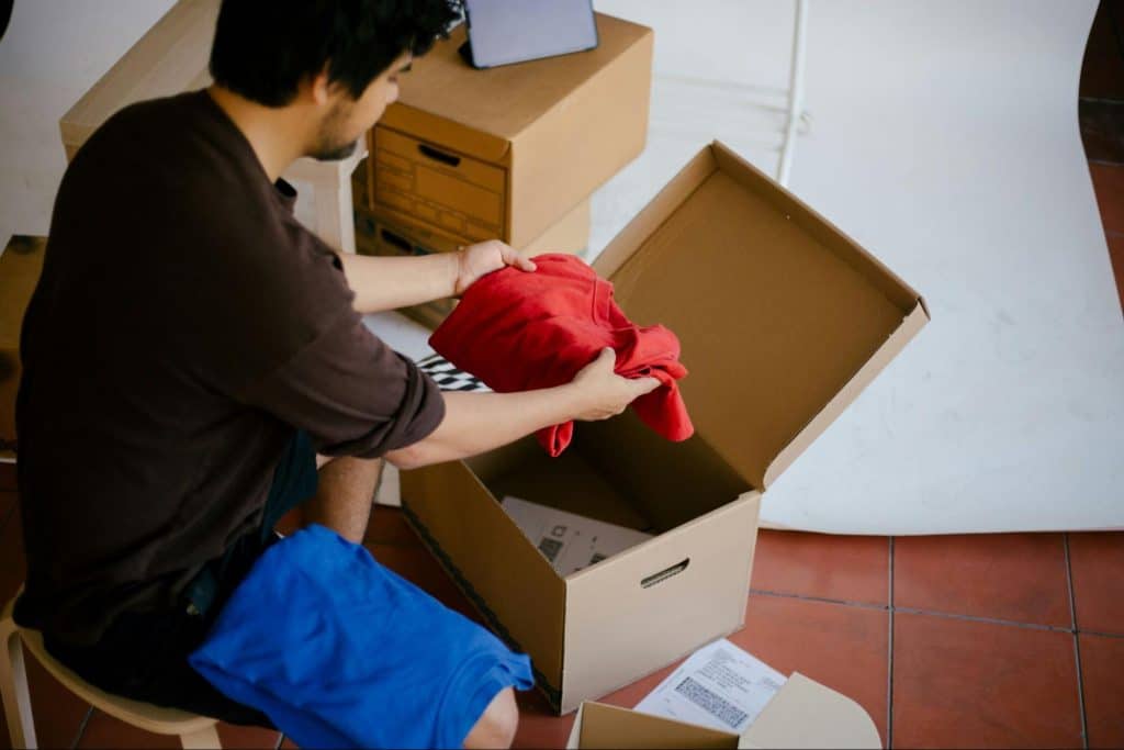 A man organizing clothes on a box.