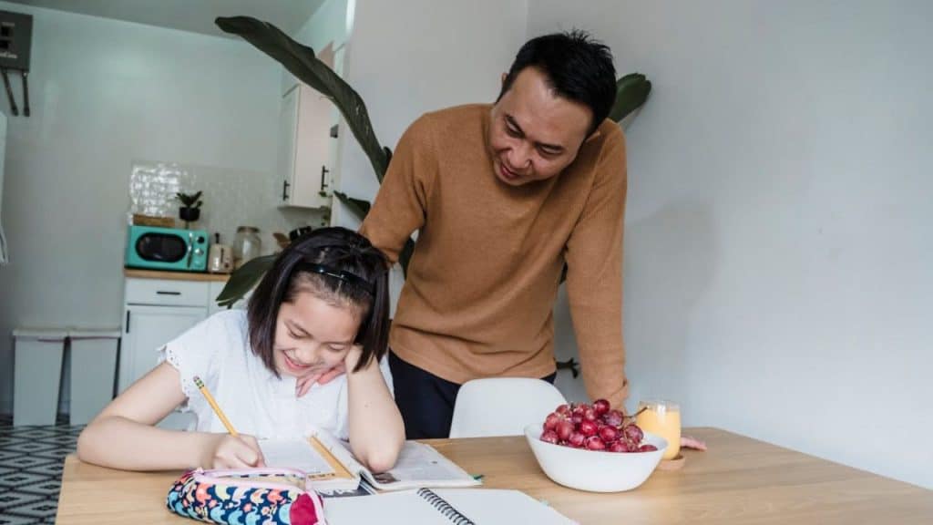 Dad and teen writing house rules together on a paper