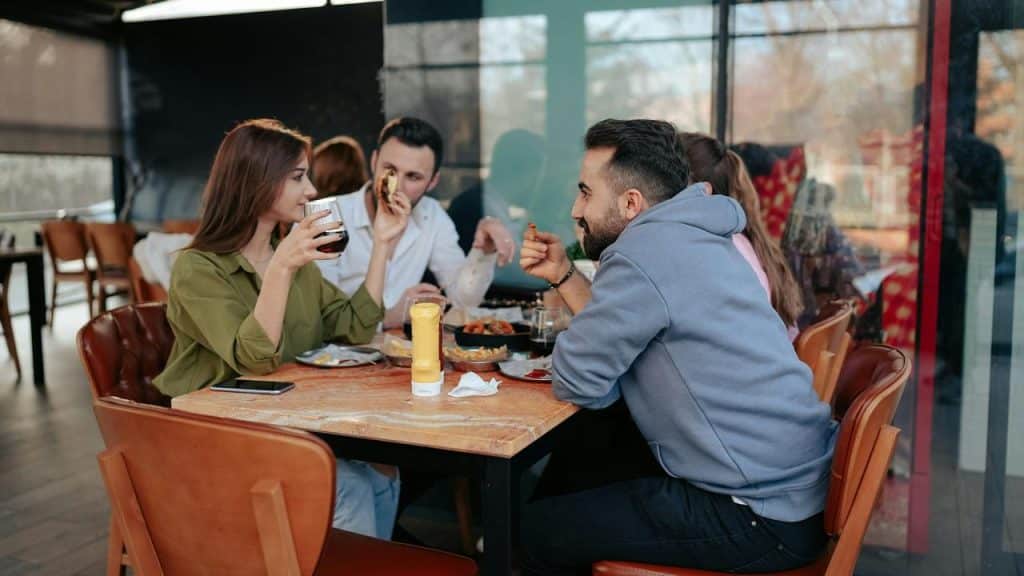 A group of friends eating and drinking at an outdoor café table.