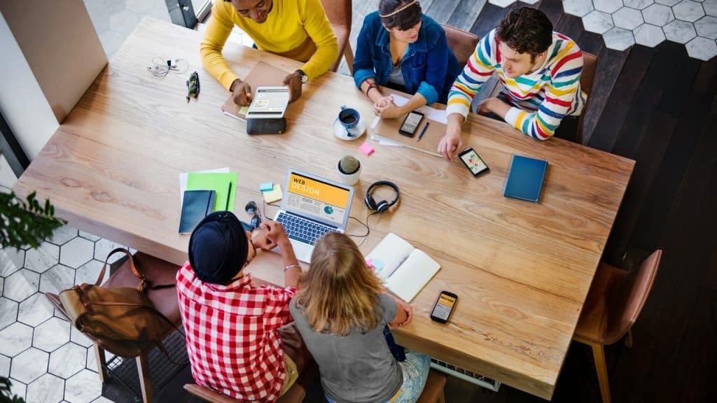 A group of people collaborating on web design around a table.