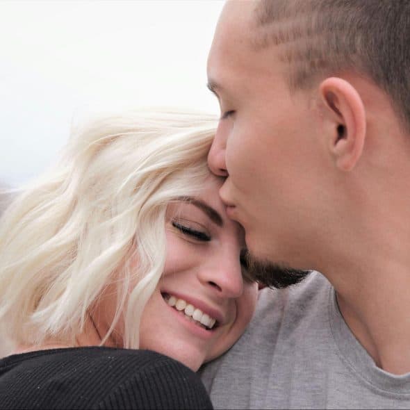 A man kissing a woman’s forehead