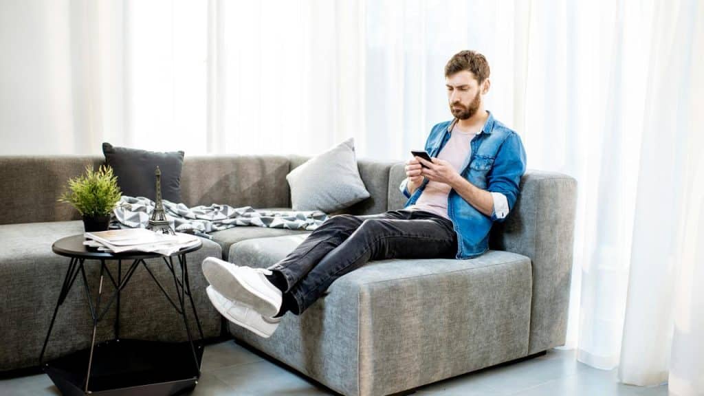 A man sitting on a sofa using his phone.