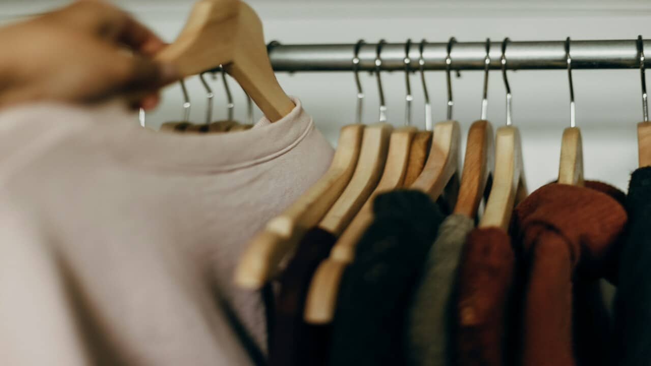 A person taking out a shirt from the closet.