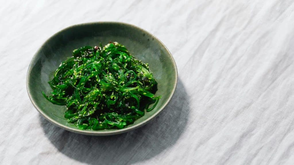 A bowl of sesame‑speckled seaweed salad on a pale cloth.