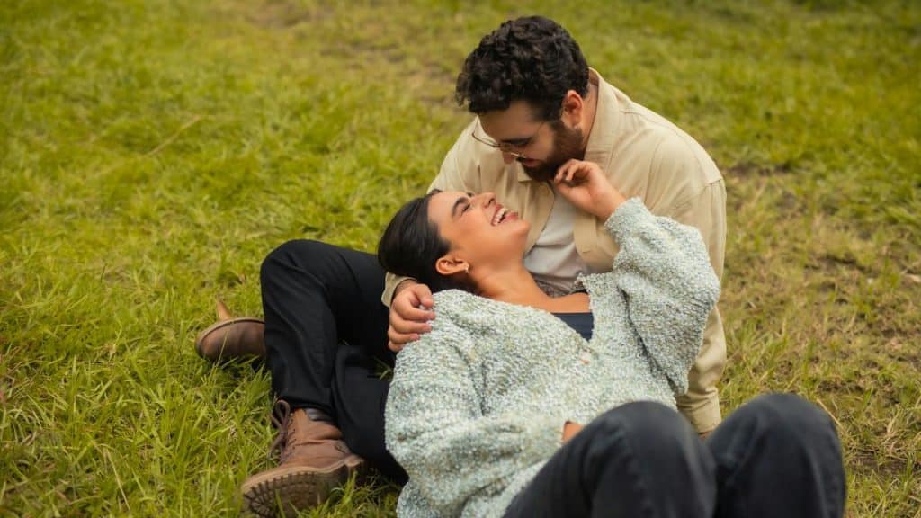 A couple lounging on grass sharing a laugh.