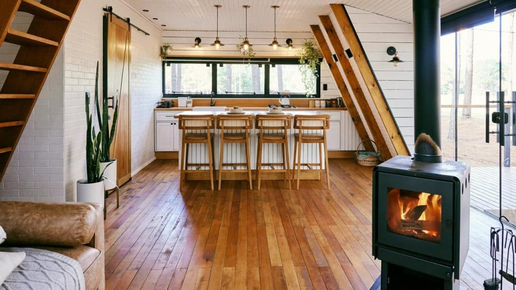 An open-plan cabin with a wood-burning stove and kitchen island.
