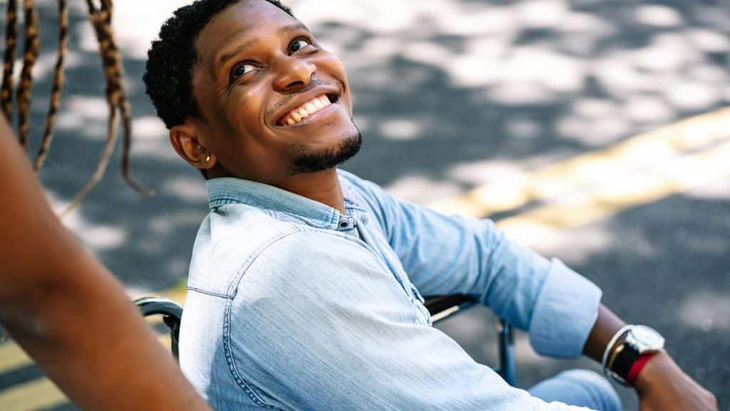 A man in a wheelchair smiling up at someone.