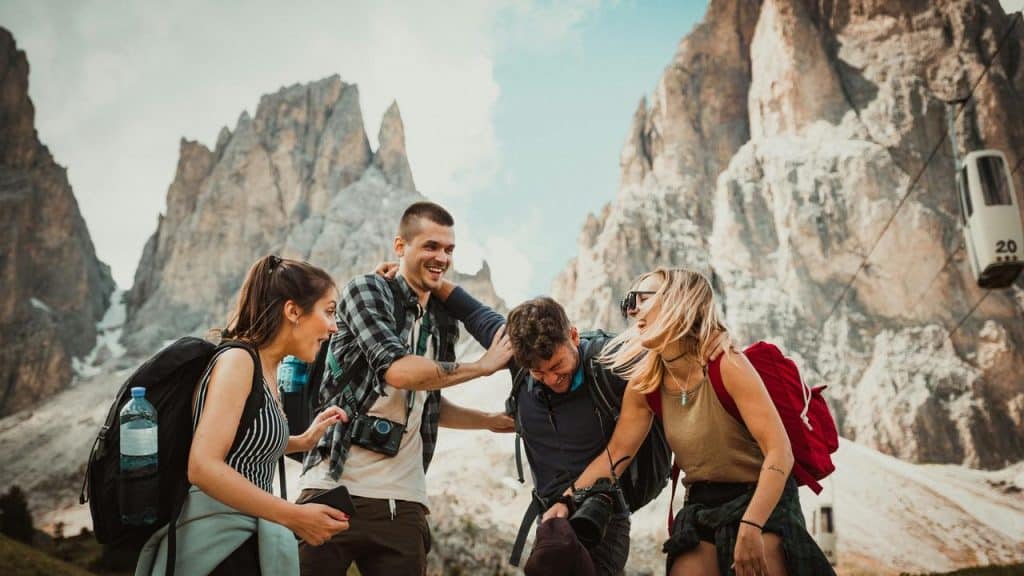 A group of four hikers laughing together against a backdrop of rugged mountain peaks.