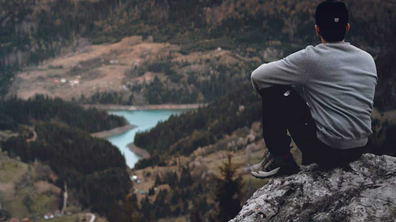 ALT Text: A man sitting peacefully on a hilltop,breathing deeply.