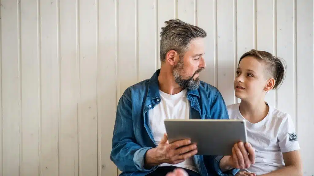 A man and a boy looking at a tablet together.