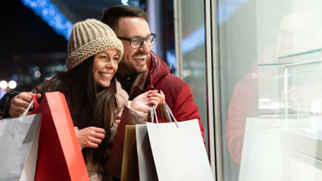 Couple walking together holding hands with shopping bags.