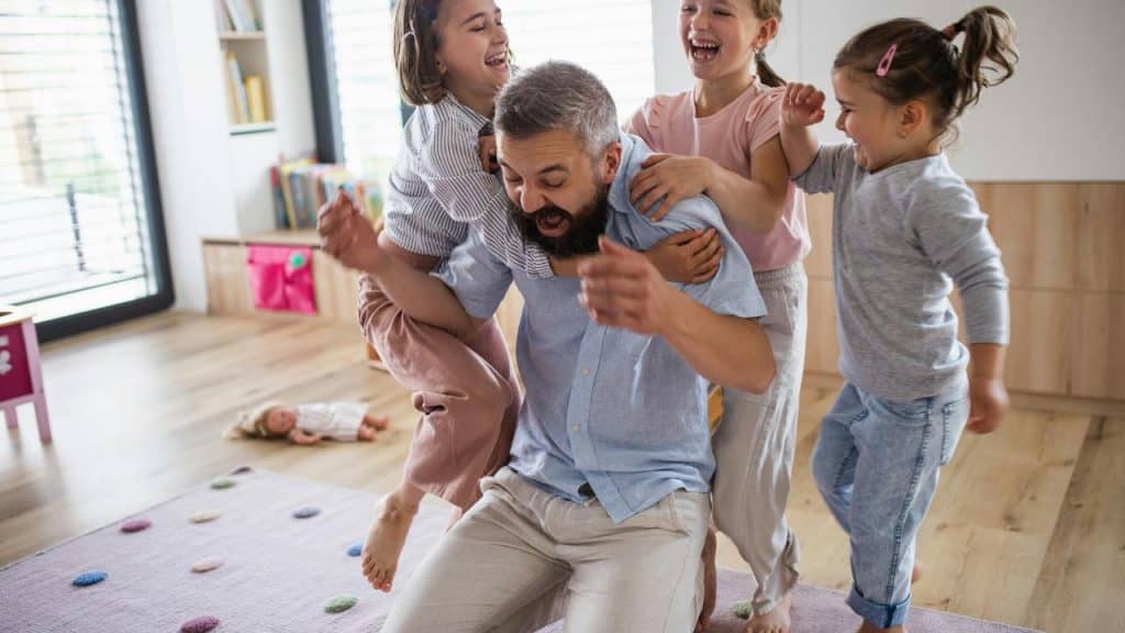 A father with three children climbing on his back.