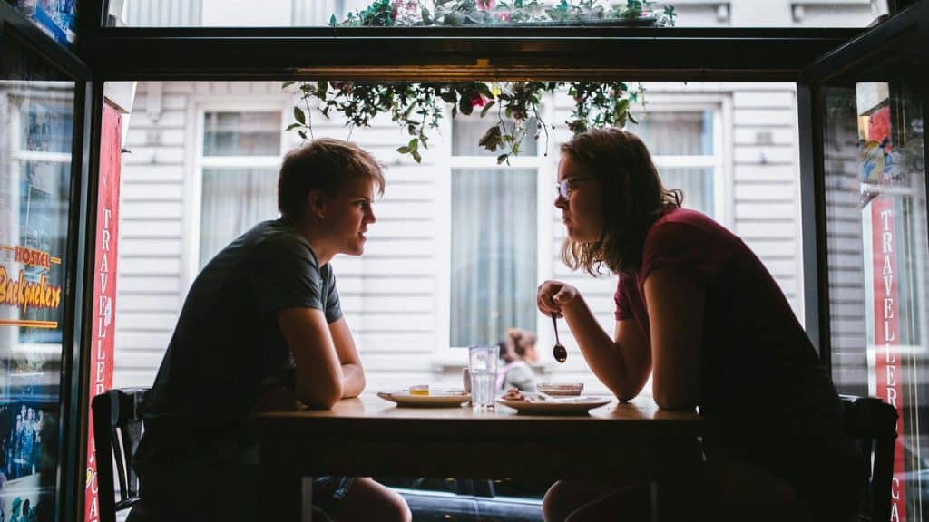 A young man and woman sharing a meal at a window-side café table.