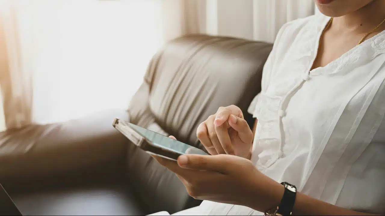 A person tapping a tablet screen while seated.