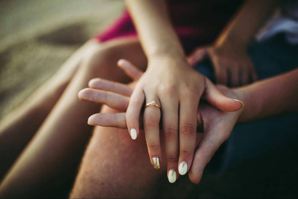 A woman with a ring and a man holding her hand